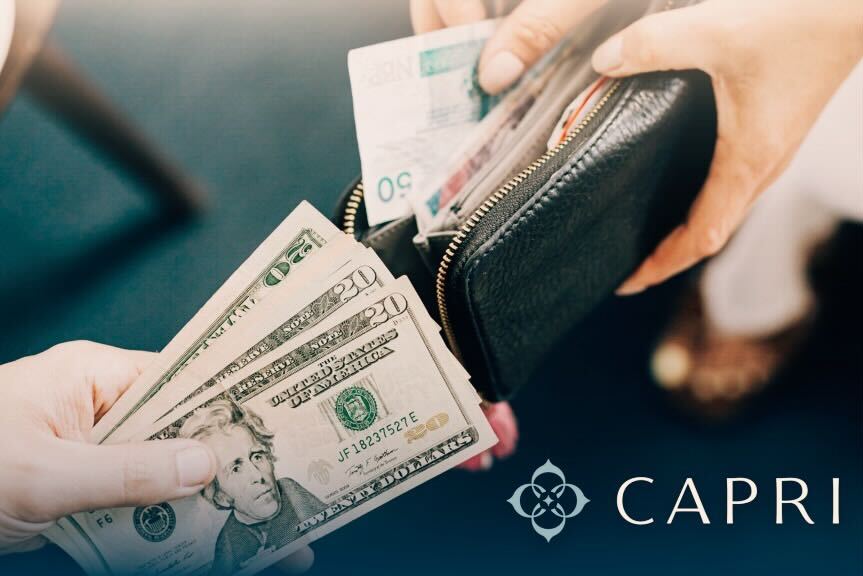 This is the header image for the Capri Temporary Housing blog titled, “The Rise of Relocation Benefits: A New Era for In-Person Work ” The image shows one person giving another cash to put in their wallet.